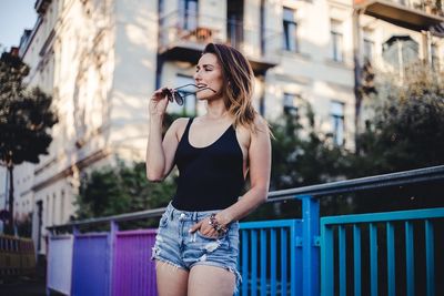 Full length of beautiful woman holding railing against buildings