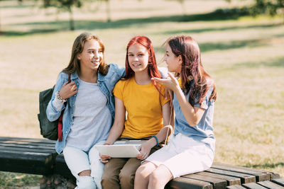 A group of teenage girls is sitting on a park bench and preparing for classes together