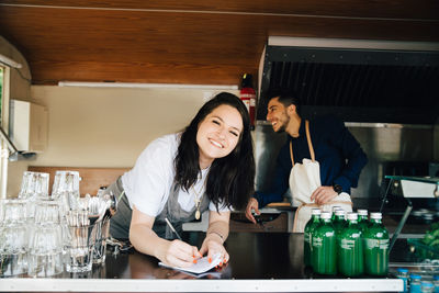 Portrait of smiling young woman standing in restaurant