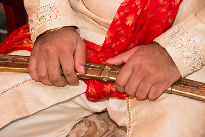 Close-up midsection of bridegroom wearing traditional clothing while holding sword