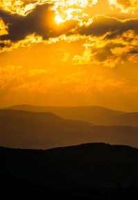 Scenic view of silhouette mountains against orange sky