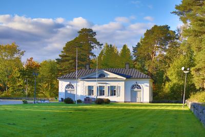 House on field by trees against sky