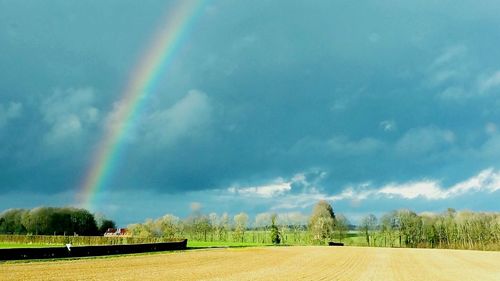 Scenic view of rainbow over field against sky