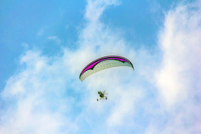 Low angle view of person paragliding against sky