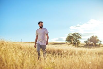 Full length of young man standing on field against sky