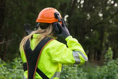 Woman working in forest forest with protective helmet