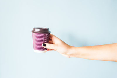 Close-up of hand holding camera over white background