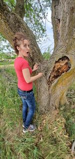 Side view of teenage girl standing on tree trunk