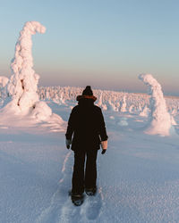 Rear view of woman walking on snow covered landscape