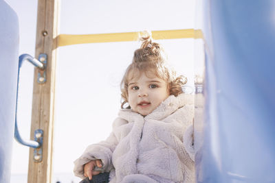 Portrait of cute baby girl sitting on slide