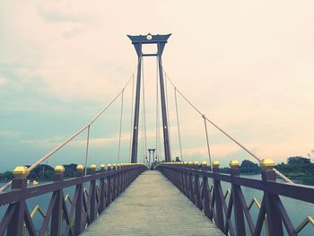 Footbridge on suspension bridge against sky