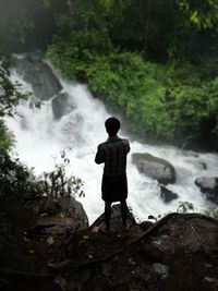 Rear view of man looking at waterfall