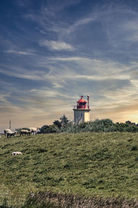 Lighthouse on field against sky