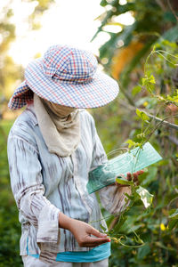 Midsection of woman with umbrella standing on field