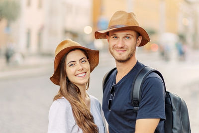 Portrait of young woman wearing hat standing in city