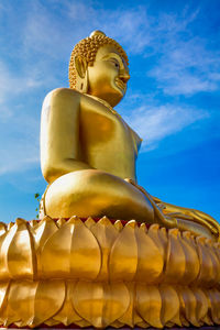 Low angle view of buddha statue against sky