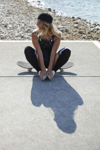 Woman sitting on skateboard at beach