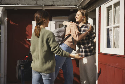 Smiling friends standing in front of wooden house