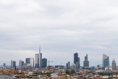 Buildings in city against cloudy sky