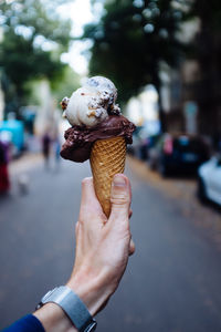 Cropped hand of man holding ice cream cone on street