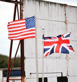 Low angle view of american and british flags against wall