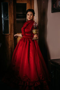 Beautiful woman in vintage 1800s early 1900s clothing red dress in old interior. historical dresses