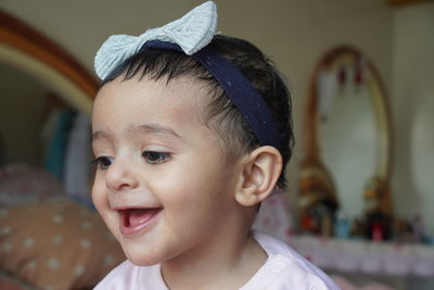 Close-up of smiling girl looking down at home