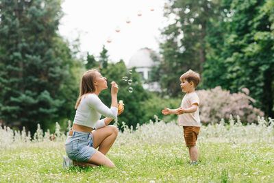 Family weekend of a mother and her little son. loving parent having fun blowing soap bubbles 