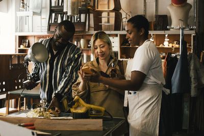 Female entrepreneur showing smart phone to customer in upcycling store