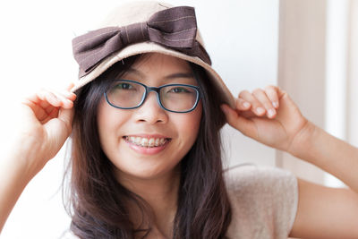 Close-up portrait of smiling young woman wearing cap