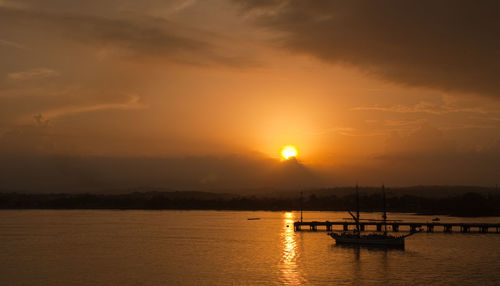 Silhouette boats moored on sea against sky during sunset