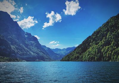 Scenic view of lake and mountains against blue sky