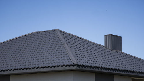 Low angle view of building roof against clear sky