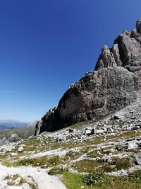 Low angle view of rocky mountain against clear blue sky