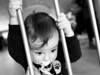 Cute boy sucking pacifier against railing