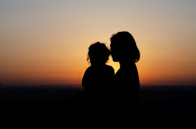 Silhouette couple against orange sky during sunset