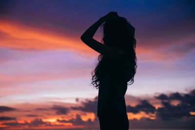 Silhouette woman standing against orange sky