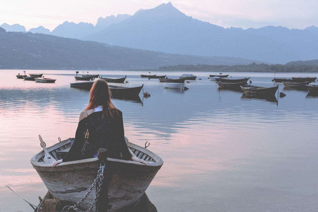 REAR VIEW OF PERSON ON LAKE AGAINST SKY