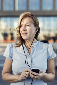 Businesswoman looking away while using mobile phone outdoors