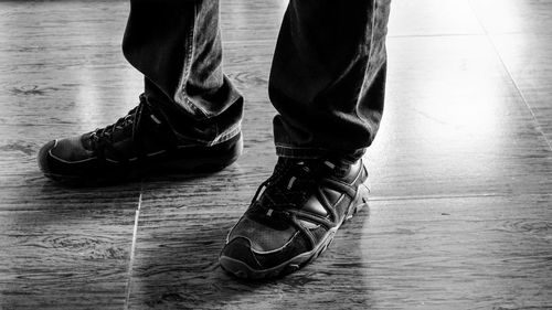 Low section of man wearing shoes while standing on hardwood floor