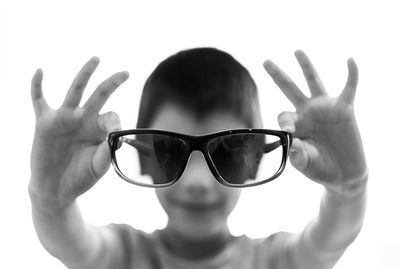 Close-up of hand holding sunglasses against white background