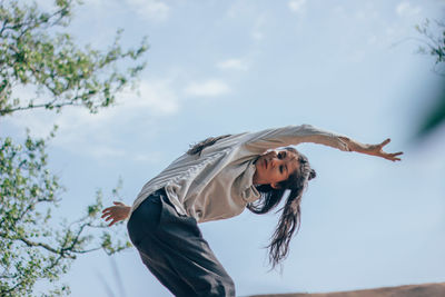 Low angle view of woman with umbrella against sky