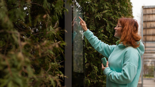 Rear view of young woman standing against trees