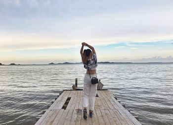 Rear view of person standing at sea shore against sky