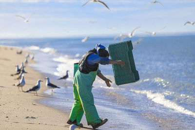 People on beach against sky, fisher, seagull 