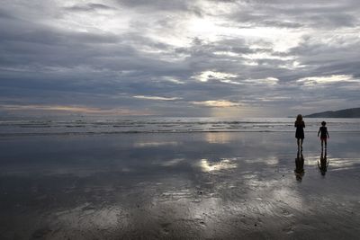 Women standing on beach against sky