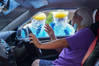 Doctor or nurse wearing ppe n95 mask face shield and personal car road screening for covid-19 virus