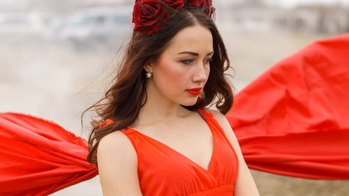 Woman in red dress looking down outdoors