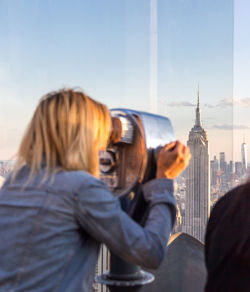 Rear view of woman photographing tower in city