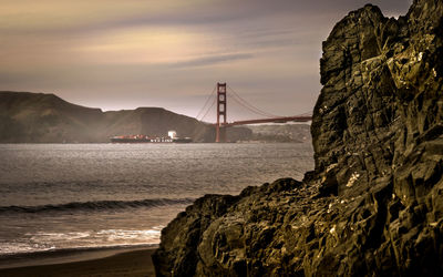 Scenic view of suspension bridge over sea against sky